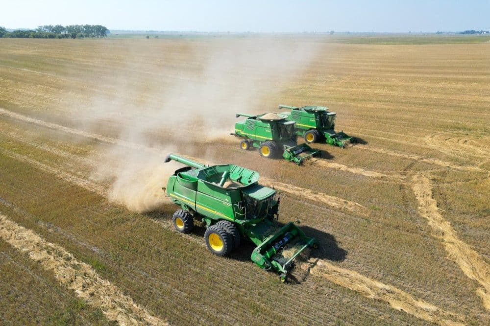 Three combines harvesting oats in a large field in North Dakota.